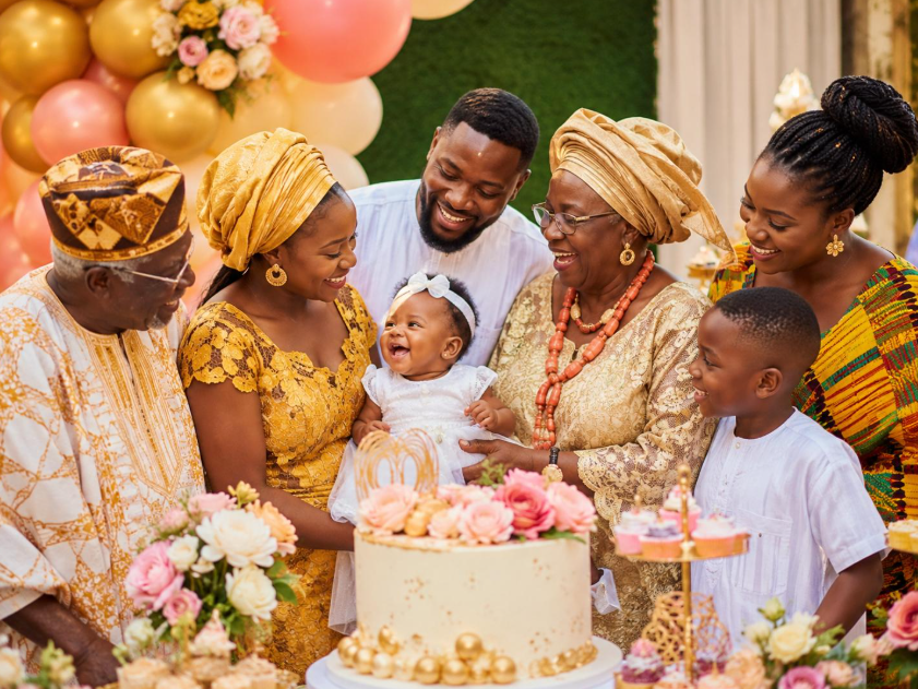 Une famille africaine réunie autour d'un bébé lors d'une fête de baptême, partageant un moment de joie